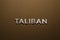 the word taliban laid with silver metal letters on rough tan khaki canvas fabric