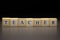 The word TEACHER written on wooden cubes isolated on a black background