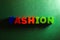 Word text Fashion spelling by wooden colorful painted letters at green craft paper background