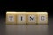 The word TIME written on wooden cubes isolated on a black background