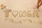 Word Tonga written in a sand