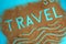 The word travel is written on the sand