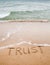 Word trust written on the sand
