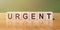 The word URGENT on wooden cubes on a table, on a beautiful background
