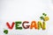 The word vegan on white background, top view. Vegan food concept. Vegan composed of beans, guacamole, vegetables and herbs
