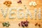 Word vegan written with sunflower seeds on a wooden board surrounded by nuts, raisins, seeds