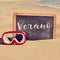 Word verano, summer in spanish, in a chalkboard on the beach