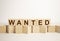 The word Wanted is made from wooden cubes on a brown background