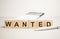 The word Wanted is made from wooden cubes on a brown background