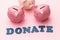 Word from wooden letters and three piggy banks on a pink background, concept on the topic of donation of money