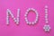 Word Word `NO` and an exclamation made with white pills  on pink background.