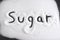 Word written with finger on pile of sugar in diet , sweet overuse and healthy nutrition concept isolated