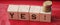 The word Yes written in black letters on wooden blocks. Message spells Yes on red background. Business, motivation and education