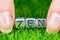 Word ZEN written in metal letters laid on grass and held between the fingers of a woman. Concept of wellness background