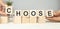 The words CHOOSE on wooden cubes.