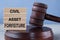 The words CIVIL ASSET FORFEITURE on wooden cubes against the background of the judge\\\'s gavel and stand