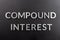 The words compound interest laid with silver metal letters on matte black surface in flat lay composition