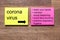 The words Corona virus with rules of conduct on.yellow and red notes sticker on a dark wooden table