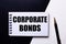 The words CORPORATE BONDS written in red on a black and white background near the pen