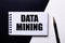 The words DATA MINING written on a black and white background near the pen