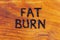 The words fat burn handritten on wooden surface with woodburner