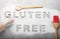 Words Gluten free written with flour and different kitchen utensils on grey background, flat lay