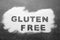 Words Gluten free written with flour on grey background, top view