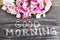 Words Good Morning with Pink Roses on a Rustic Wooden Background