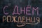Words Happy Birthday written in Russian language on blackboard