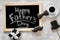 Words happy Father`s day written on blackboard. Black tie, mustache and hat cookies. Grey stone background top view