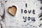 Words I love you hand-painted on dark table covered with white flour and heart made from raw cookie dough
