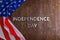 the words independence day laid on brown wooden planks surface with crumpled unated states of america flag