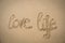 The words love life written in the sand