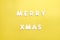 The words Merry xmas made of wooden letters on yellow background