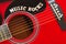 Words Music Rocks with wooden letters, closeup on a surface of red acoustic guitar. Music entertainment background