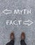 Words Myth, Fact and two arrows on the ground in front of a man\'s shoes