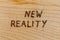 The words new reality handwritten with woodburner tool on flat wood surface