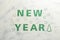 Words NEW YEAR made of flour on green background, top view