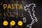 Words pasta made of cooked spaghetti and dry pasta on the black background with frame of country Italy written by chalk