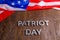 the words patriot day laid with silver metal letters on wooden board surface with crumpled usa flag