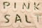 The Words Pink Salt Cutout from a Layer of Pink Salt on Green