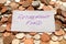 The words retirement fund written in purple pen on white paper on top of a pile of British coins