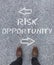 Words Risk, Opportunity and arrows written on the ground in front of a man\'s shoes