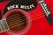 Words Rock Music with wooden letters, closeup on a surface of red acoustic guitar. Music entertainment background