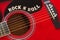 Words Rock N Roll with wooden letters, closeup on a surface of red acoustic guitar. Music entertainment background