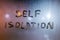 The words self isolation handwritten on wet window glass at night - close-up fuul frame picture with selective focus