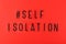 Words self isolation and hashtag on red background