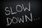 The words Slow Down written on a Blackboard