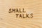The words small talks handwritten with woodburner on flat plywood surface