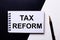 The words TAX REFORM written in red on a black and white background near the pen